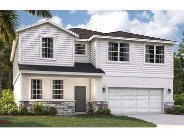 Charming two-story home featuring stone accents, white siding, and an attached two-car garage at 9568 Starling Loop, Leesburg, FL 34788