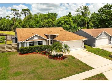 Charming single-story home with a well-manicured lawn, lovely landscaping, and a two-car garage at 11005 Cypress Leaf Dr, Orlando, FL 32825
