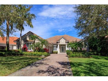 Charming one-story home with a well-manicured lawn, lush landscaping, and a brick driveway leading to the entrance at 11139 Camden Park Dr, Windermere, FL 34786