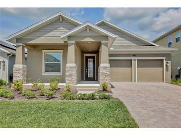 Charming single-story home featuring a two-car garage, landscaped yard, and stone-accented columns at 11725 Language Way, Orlando, FL 32832