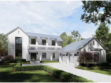 Beautiful white farmhouse with a three-car garage and brick-paved driveway surrounded by lush landscaping at 1256 Water Maple Dr, Oakland, FL 34787