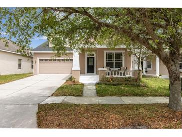 Charming beige two-story home featuring a cozy front porch and attached two-car garage at 1825 Saffron Plum Ln, Orlando, FL 32828