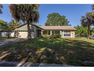 Charming single-story home featuring tropical landscaping, stone accents, and an attached two-car garage at 3220 Cardigan Ct, Orlando, FL 32812