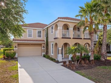 Inviting two-story home with a red tile roof, a two-car garage, and lush tropical landscaping at 4200 Oaktree Dr, Davenport, FL 33837