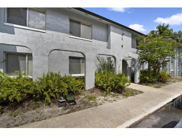 Inviting two-story condo with arched facade detail, manicured shrubbery, and walkway at 4713 S Texas Ave # 4713D, Orlando, FL 32839