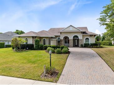 Charming single-story home with a well-manicured lawn, brick driveway, and inviting front entrance at 5509 Meadow Hill Loop, Lady Lake, FL 32159