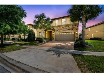 Beautiful two-story home featuring a stone facade, manicured landscaping, and a spacious two-car garage at 8808 Macapa Dr, Kissimmee, FL 34747