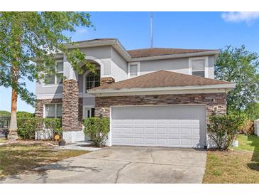Two-story home with stone accents, a two car garage, and well-maintained landscaping at 9919 Cypress Knee Cir, Orlando, FL 32825