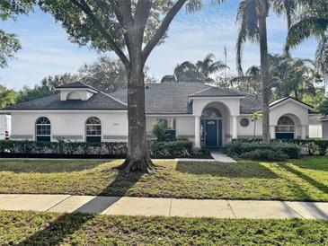 Charming one-story home with a well-manicured lawn, arched entry, and mature landscaping at 1200 Montheath Cir, Ocoee, FL 34761