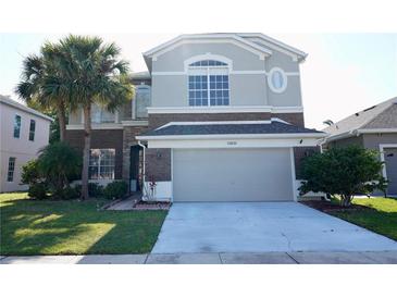 Two-story home featuring a large driveway, a 2-car garage, and a beautiful lawn with mature landscaping at 13520 Meadow Bay Loop, Orlando, FL 32824