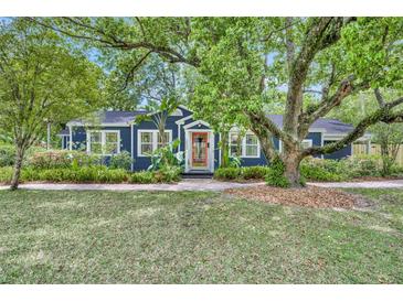 Charming blue home with a lush green lawn and mature trees, exuding curb appeal at 2004 E Marks St, Orlando, FL 32803