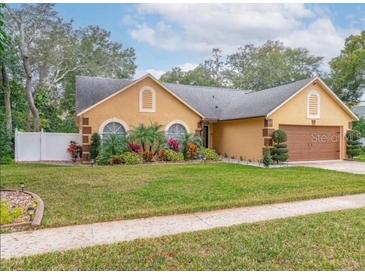 Charming single-story home featuring a well-manicured lawn and lush landscaping at 400 Shelby Ct, Apopka, FL 32712