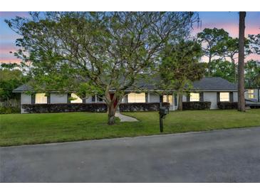 Charming single-story home with a well-manicured lawn, mature landscaping, and a brick facade at 401 Sanford Ave, Longwood, FL 32750