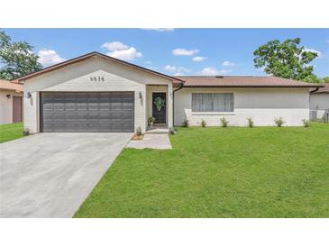 Charming white brick home featuring a well-manicured lawn, gray garage door, and inviting front entrance at 4636 Mesa Verde Dr, St Cloud, FL 34769