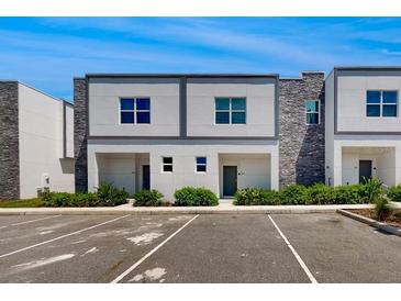 Modern townhome exterior with stone accents, manicured landscaping, and convenient parking at 485 Famagusta Dr, Davenport, FL 33896