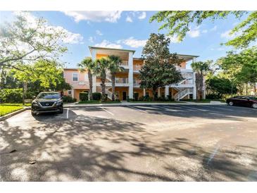 Three-story peach-colored condo with a parking lot, mature trees, and clear blue skies at 509 New Providence, Davenport, FL 33897