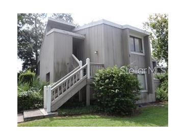 Two-story exterior view featuring a wooden staircase leading to the entrance at 5926 Peregrine Ave # A13, Orlando, FL 32819