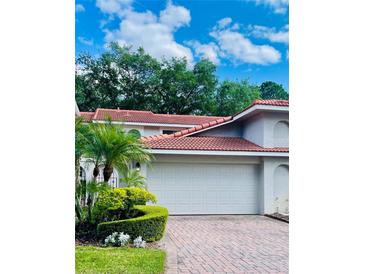 Two car garage with a brick driveway and beautiful green landscaping at 7629 Chapelhill Dr, Orlando, FL 32819