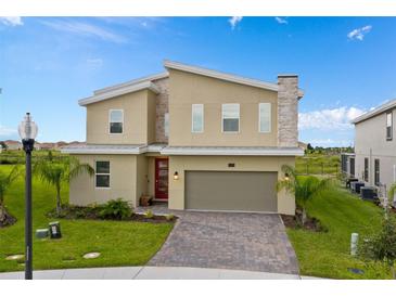 Charming two-story home featuring modern architecture, a stone chimney, and a red front door at 905 Ocean Course Ave, Davenport, FL 33896