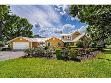Charming two-story home with a well-manicured lawn, colorful flower beds, and attached garage at 11200 Lane Park Rd, Tavares, FL 32778