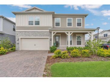 Charming two-story home featuring a stone facade, front porch, and well-maintained landscaping at 13640 Haulover Beach Ln, Orlando, FL 32827