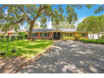 Charming brick home featuring a well-manicured lawn, mature trees, and an inviting front entrance at 1511 Crestline St, Orlando, FL 32806