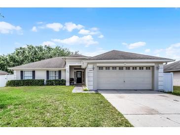Charming one-story home with a well-manicured lawn, mature landscaping, and an attached two-car garage at 1802 Hagen Ct, St Cloud, FL 34771