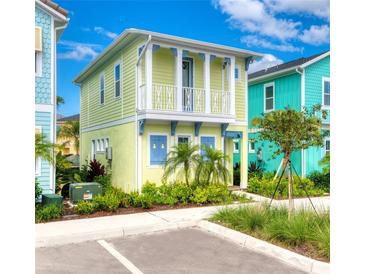 Charming two-story coastal cottage with colorful facade, white balcony, manicured landscaping, and sidewalk access at 2978 Latitude Ln, Kissimmee, FL 34747