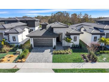 Stunning home showcasing modern architecture, a manicured lawn, and a stylish gray tiled driveway and roof at 3020 Kensington Ave, Davenport, FL 33837