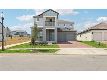 Two-story home featuring a gray exterior, balcony, brick driveway, and attached two-car garage at 5260 Citrus Leaf Blvd, Winter Garden, FL 34787