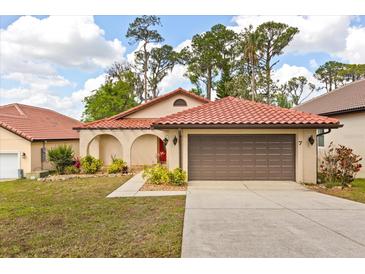 Charming single-story home with a red tile roof, arched entryway, and well-manicured landscaping at 7 Forest Ln, Eustis, FL 32726