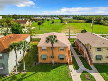 Bright two-story townhome featuring a well-maintained lawn with lush green grass and palm trees at 734 Michigan Ct # 2, St Cloud, FL 34769