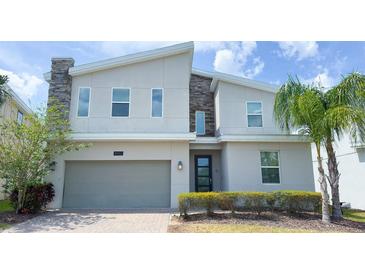 Contemporary two-story home featuring a stone accent wall and well-manicured landscaping at 8912 Cabot Cliffs Dr, Davenport, FL 33896