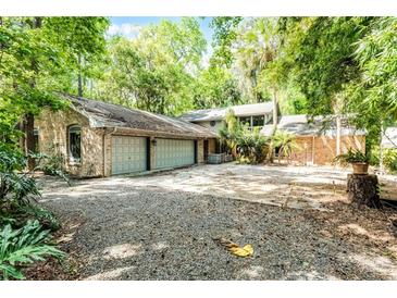 Sprawling single story brick home featuring an attached three car garage and long driveway at 102 Wild Plum Ln, Longwood, FL 32779