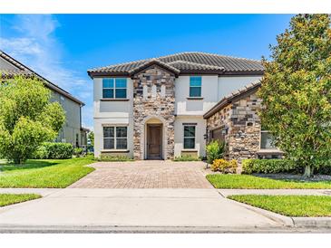 Charming two-story home featuring a stone facade, well-manicured lawn, and a paved driveway leading to the entrance at 11689 Hampstead St, Windermere, FL 34786