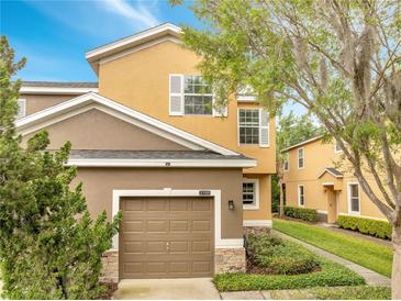 Two-story home featuring a two-car garage, tan and brown stucco, manicured landscaping, and lovely curb appeal at 3166 Rodrick Cir, Orlando, FL 32824