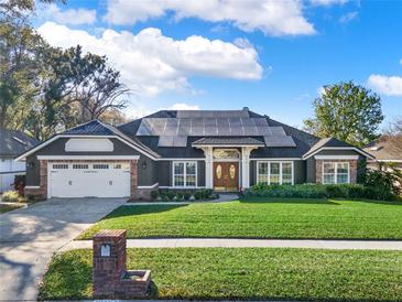 Charming home featuring a two-car garage, solar panels, beautiful landscaping, and a well-manicured lawn at 4916 Winwood Way, Orlando, FL 32819