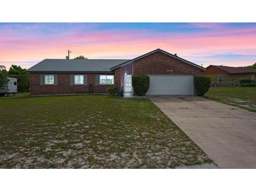 Charming brick home featuring a well-maintained lawn and attached two-car garage at 549 Mcneal Dr, Deltona, FL 32725