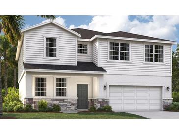 Charming two-story home with a modern design, stone accents, a two-car garage and well-manicured lawn at 1211 Normandy Dr, Haines City, FL 33844