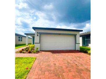 Charming one-story home featuring a brick driveway, a two-car garage, and manicured landscaping at 6028 Bimini Ave, Haines City, FL 33844