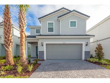 Charming two-story home featuring a gray exterior, well-maintained landscaping, and a spacious two-car garage at 7352 Oakmoss Loop, Davenport, FL 33837
