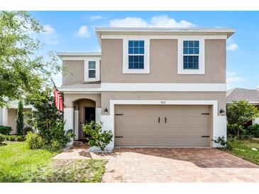 Two-story home with brick driveway, attached garage and manicured landscaping at 812 Marcel Loop, Davenport, FL 33837