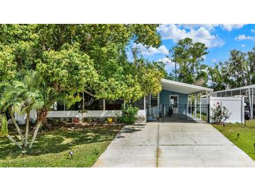 Charming blue home featuring a well-maintained lawn and a driveway, shaded by mature trees at 133 Moss Dr, Debary, FL 32713