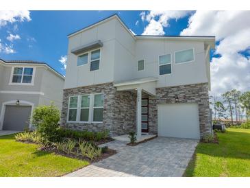 Contemporary two-story home boasting a stone facade, covered entryway, and a well-manicured front yard at 2004 Fleming Mist Pl, Kissimmee, FL 34747