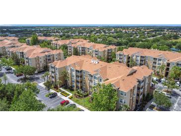 A beautiful aerial view of multiple apartment buildings featuring large parking lots and lush trees at 2781 Almaton Loop # 404, Kissimmee, FL 34747