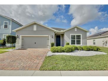 Charming single-story home featuring a brick driveway, two-car garage, and well-manicured landscaping at 299 Whirlaway Dr, Davenport, FL 33837