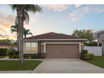 Charming single-Gathering home featuring a two-car garage, well-manicured lawn, and tropical landscaping at 427 Highland Meadows St, Davenport, FL 33837