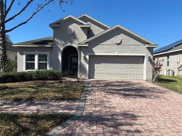 Charming single-Gathering home featuring a brick driveway and a neutral-toned stucco exterior at 457 Bridgeford Crossing Blvd, Davenport, FL 33837