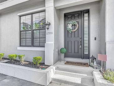 Charming home exterior featuring a decorative wreath, manicured shrubs, and inviting entrance at 12955 Cats Claw Ln, Orlando, FL 32828
