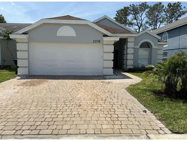 Charming single-story home with a well-manicured lawn and a brick driveway at 2218 Newt St, Orlando, FL 32837